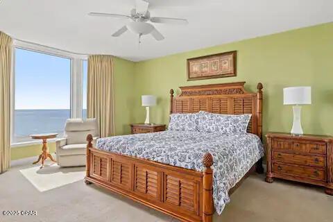 carpeted bedroom featuring a water view and ceiling fan