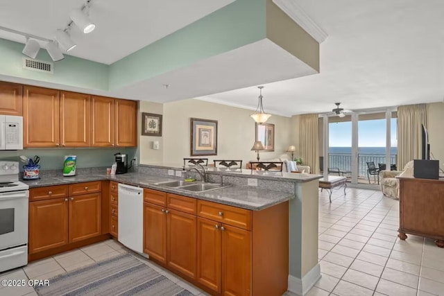 kitchen featuring kitchen peninsula, white appliances, a wall of windows, and sink