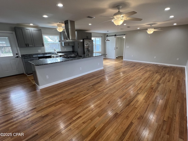 kitchen featuring stainless steel fridge with ice dispenser, ventilation hood, gray cabinets, and dark stone counters