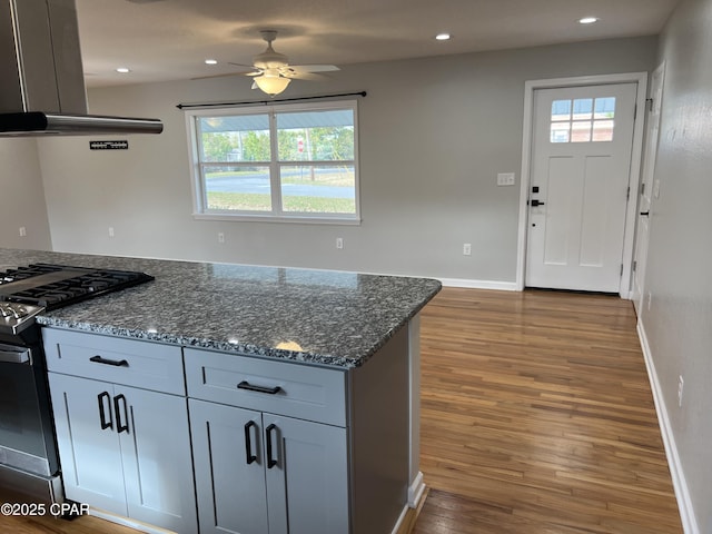 kitchen with gas stove, extractor fan, plenty of natural light, and dark stone countertops