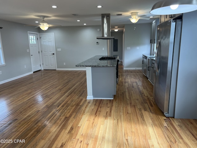 kitchen with hardwood / wood-style flooring, extractor fan, stainless steel refrigerator, and dark stone counters