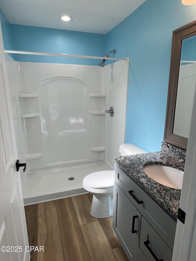 bathroom featuring hardwood / wood-style floors, toilet, a shower, and vanity