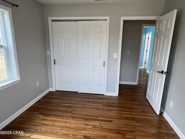 unfurnished bedroom featuring dark hardwood / wood-style flooring and a closet