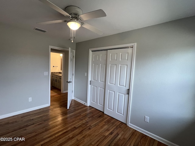 unfurnished bedroom with ceiling fan, dark wood-type flooring, and a closet