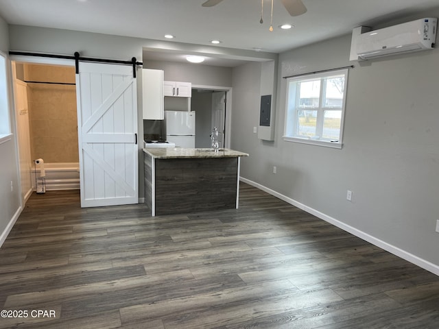 kitchen featuring white cabinetry, a barn door, light stone counters, white refrigerator, and a wall unit AC