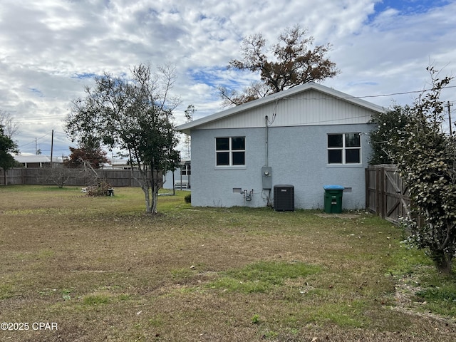 back of house with central AC unit and a lawn