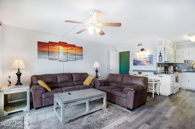 living room with ceiling fan, sink, and dark wood-type flooring