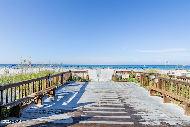 wooden deck with a water view and a beach view