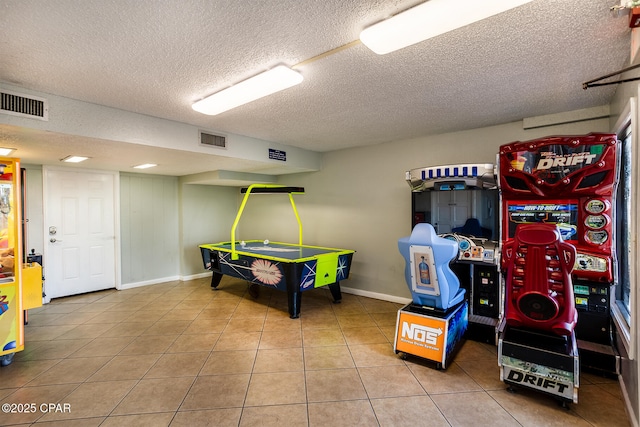 recreation room featuring tile patterned flooring and a textured ceiling