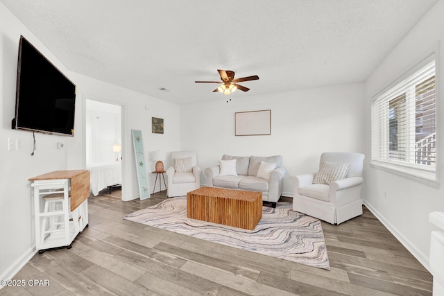 living room featuring ceiling fan, wood-type flooring, and a textured ceiling