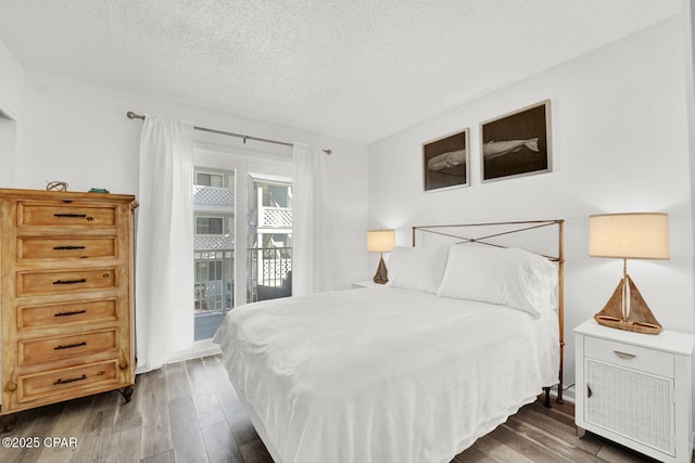 bedroom featuring dark hardwood / wood-style flooring, a textured ceiling, and access to outside