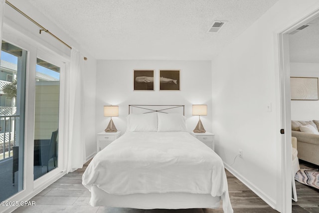 bedroom featuring hardwood / wood-style floors, a textured ceiling, and access to outside