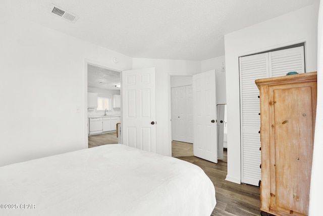 bedroom with a closet, sink, dark wood-type flooring, and a textured ceiling