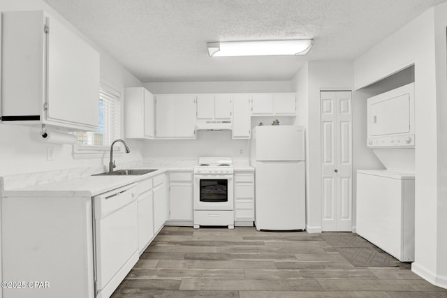 kitchen featuring white cabinets, sink, white appliances, and stacked washer / dryer