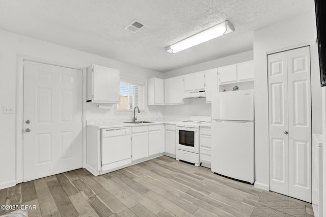 kitchen with white cabinets, white appliances, sink, and a textured ceiling