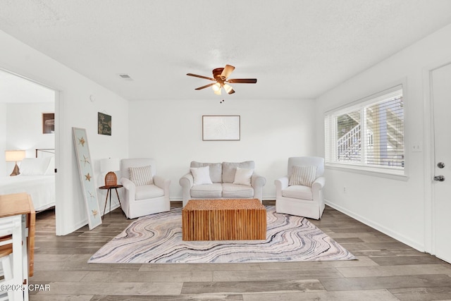 living room with a textured ceiling, dark hardwood / wood-style floors, and ceiling fan