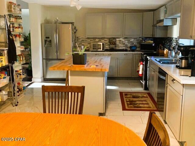 kitchen with gray cabinetry, sink, wooden counters, decorative backsplash, and appliances with stainless steel finishes