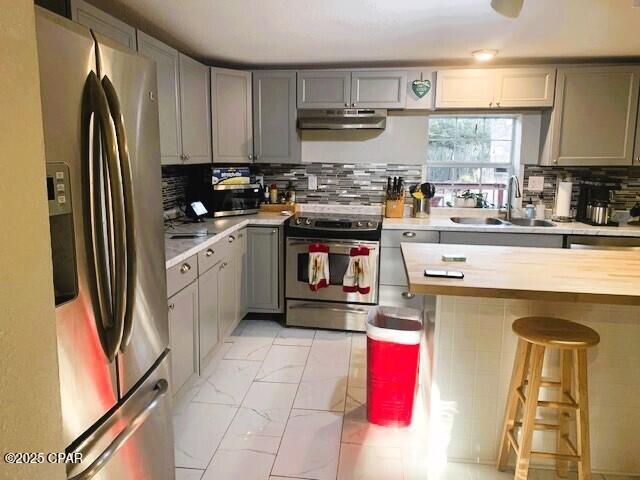 kitchen with gray cabinets, sink, stainless steel appliances, and tasteful backsplash