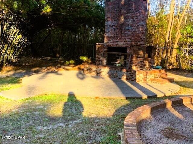 view of yard featuring an outdoor brick fireplace and a patio area