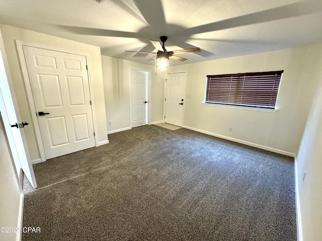 unfurnished bedroom with ceiling fan and dark colored carpet