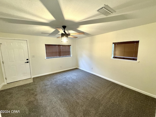 carpeted empty room featuring ceiling fan and a textured ceiling