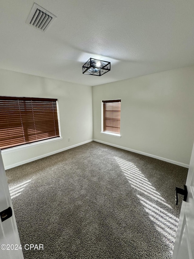 carpeted empty room with a textured ceiling