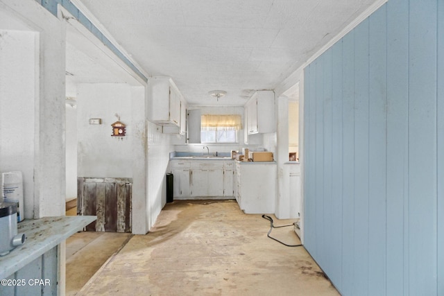 kitchen with white cabinetry, sink, and wooden walls