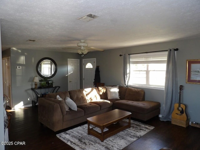 living room with ceiling fan, a textured ceiling, and dark wood-type flooring