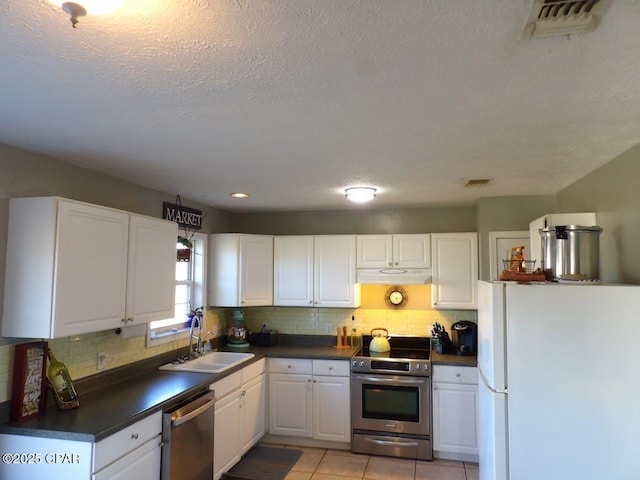 kitchen featuring white cabinetry, sink, backsplash, light tile patterned flooring, and appliances with stainless steel finishes