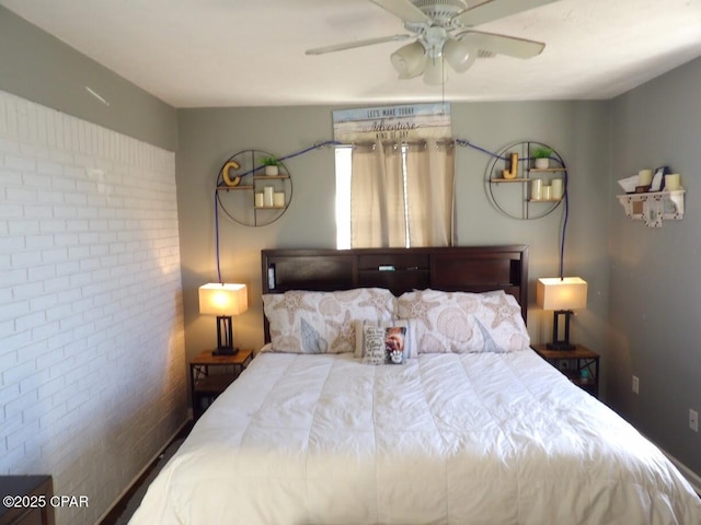 bedroom with ceiling fan and brick wall