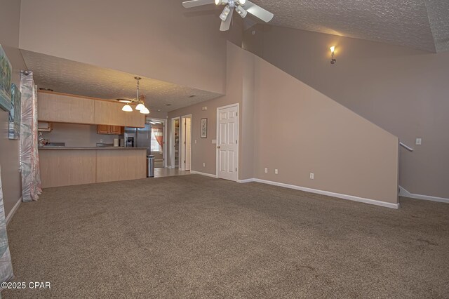 unfurnished living room featuring ceiling fan with notable chandelier, high vaulted ceiling, carpet, and a textured ceiling