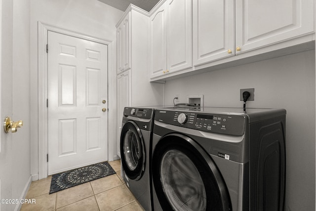 clothes washing area featuring washer and clothes dryer, light tile patterned flooring, cabinet space, and baseboards