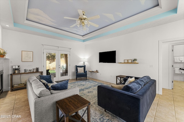 living area with french doors, a tray ceiling, a fireplace, and light tile patterned flooring