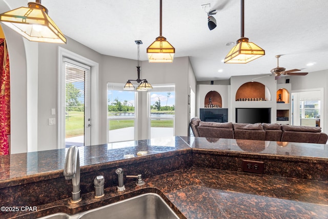 kitchen with pendant lighting, sink, ceiling fan, built in features, and a textured ceiling