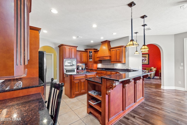 kitchen with pendant lighting, a breakfast bar, premium range hood, decorative backsplash, and kitchen peninsula