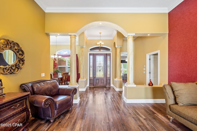 entryway with decorative columns, crown molding, dark hardwood / wood-style floors, and a notable chandelier