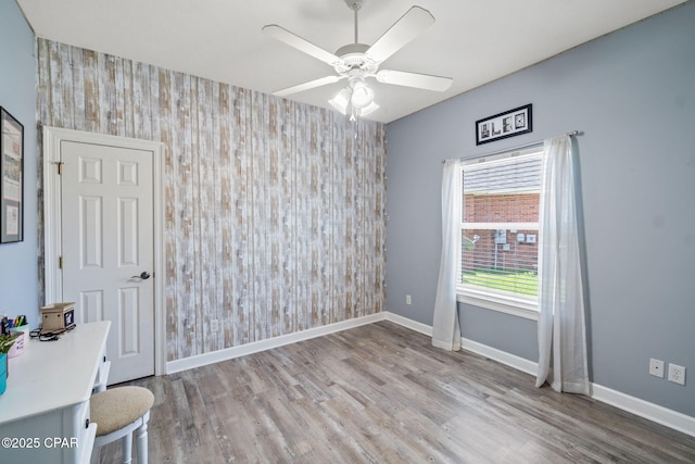 unfurnished room with ceiling fan, light hardwood / wood-style floors, and wooden walls