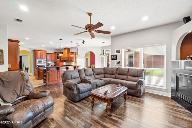 living room with ceiling fan, dark hardwood / wood-style flooring, and a textured ceiling