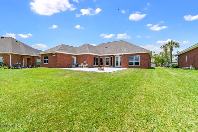 rear view of property featuring a lawn, a patio area, and a fire pit