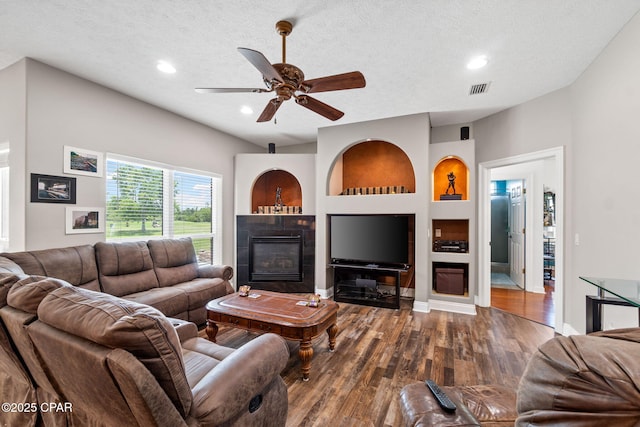 living room with hardwood / wood-style floors, ceiling fan, a textured ceiling, and a tiled fireplace