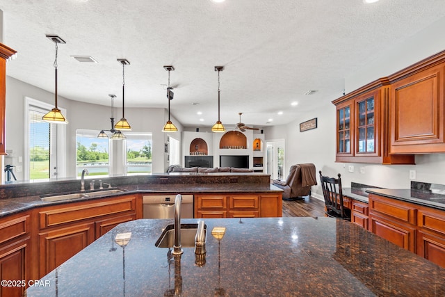 kitchen featuring a textured ceiling, decorative light fixtures, stainless steel dishwasher, and sink