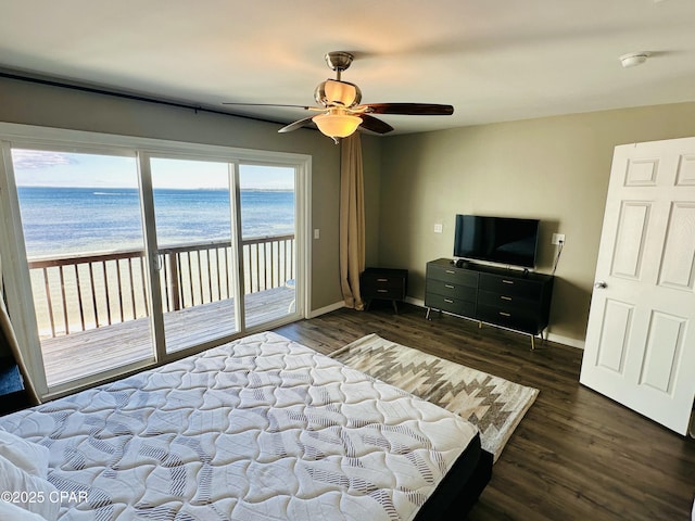 bedroom with access to exterior, a view of the beach, dark hardwood / wood-style flooring, and ceiling fan