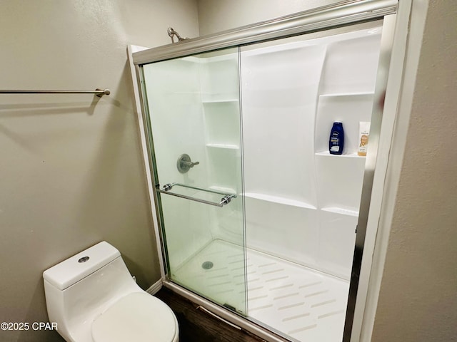 bathroom with a shower with door and toilet