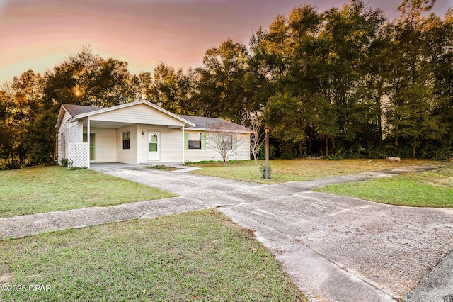 view of front of house with a carport, concrete driveway, and a yard