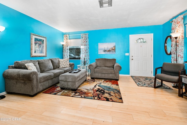 living room featuring visible vents, baseboards, and wood finished floors