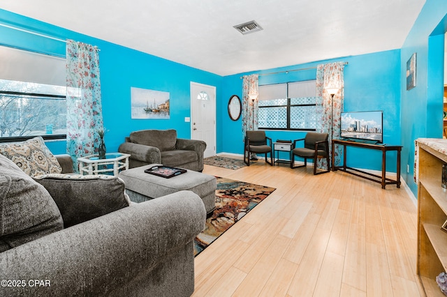 living area with visible vents, baseboards, and wood finished floors