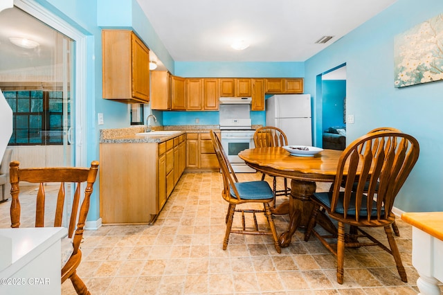 kitchen with visible vents, under cabinet range hood, light countertops, white appliances, and a sink