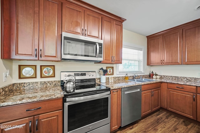 kitchen with light stone counters, sink, appliances with stainless steel finishes, and dark hardwood / wood-style floors