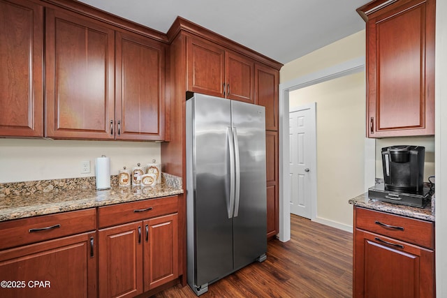 kitchen with light stone countertops, dark hardwood / wood-style flooring, and stainless steel refrigerator