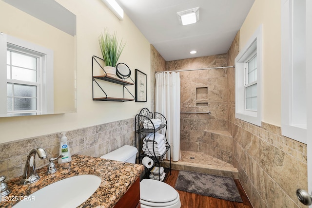 bathroom featuring vanity, toilet, walk in shower, and tile walls